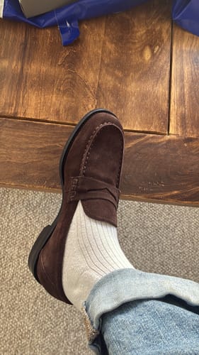 לקוחה נועלת מוקסין זמש חום מדגם Linn עם גרב לבנה וג'ינס.