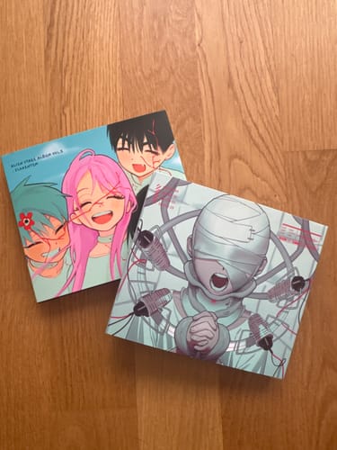 Customer's two Alien Stage albums, Vol. 1 and Vol. 2, displayed with their colorful anime-style covers on a wooden surface.