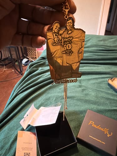 Customer holding a custom photo engraved pendant necklace featuring two people and the name 'AuntieCoco' over its gift box.