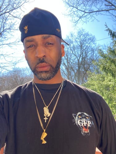 Reviewer standing outdoors wearing the black SILENT MOVES TEE, showing the front logo.