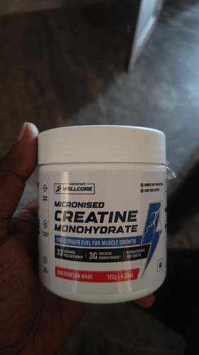 Customer holding a white tub of Wellcore Micronised Creatine Monohydrate in Watermelon Wave flavor.