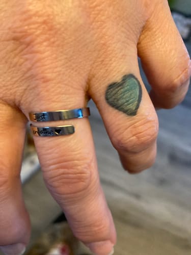 Close-up of a reviewer wearing the silver Just Breathe Ring, showing the 'just breathe' engraving.