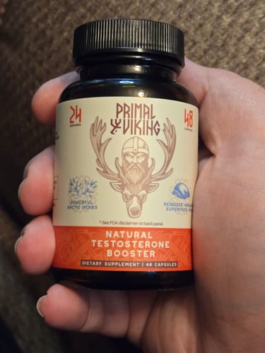 Reviewer holding a dark bottle of Primal Reindeer Testosterone Support supplement in their hand.