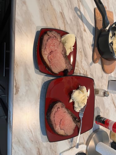 Reviewer's two plates with thick slices of Pre-Cooked Smoked Prime Rib showing a pink center and mashed potatoes.