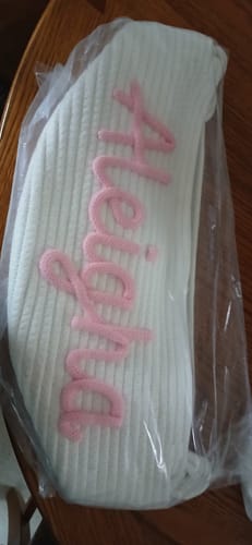 Customer's personalized knitted basket with the name 'Aleigha' seen through its clear plastic packaging.