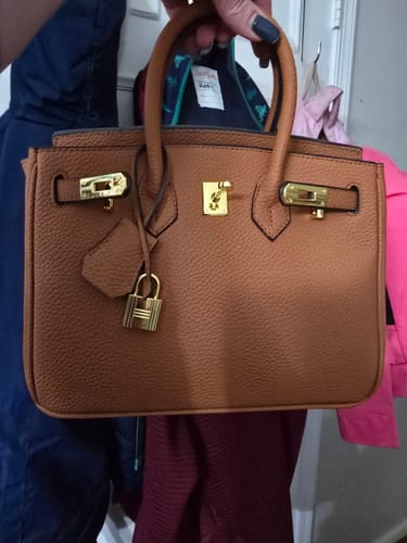 Customer holding up their brown Warkin Bag, showing its pebbled texture and gold hardware.