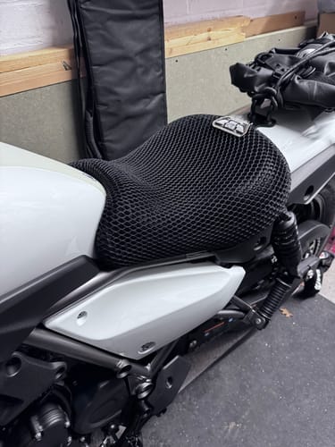 Customer's black Wind Rider Seat Cover with a mesh texture fitted on a white motorcycle seat.