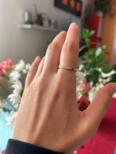 Customer's hand wearing the gold Angelica® Angel Number Band with the '999' engraving on their index finger.