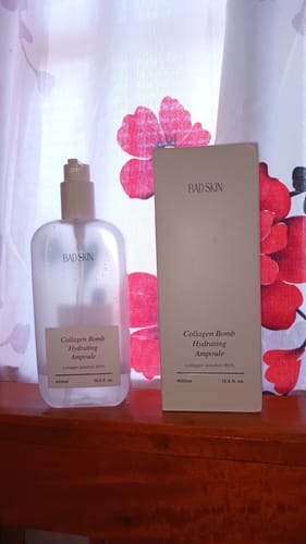Customer's Bad Skin Korean Collagen Bomb Hydrating Ampoule bottle next to its white box on a wooden surface.