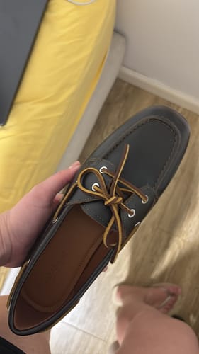 לקוחה מחזיקה בידה מוקסין בודד מדגם Hillary בצבע כהה עם שרוכים חומים.