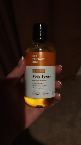 Customer holding a bottle of the Caramel Glaze Body Splash, showing the golden oil.