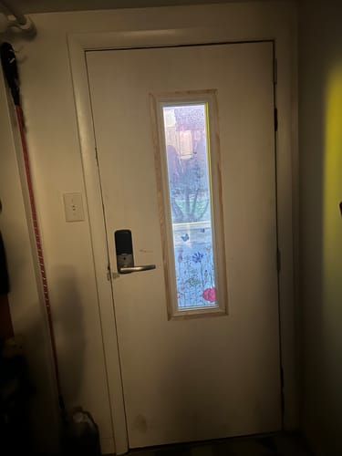 Customer's unpainted Glass and Frame Kit installed in a white door, with a floral cling on the window.