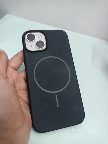 Reviewer holding the black Anti Dust Magsafe Silicone Case, showing the MagSafe symbol on the back.