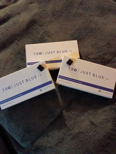 Customer's three Just Blue boxes with two individual dark troches displayed on a fabric.