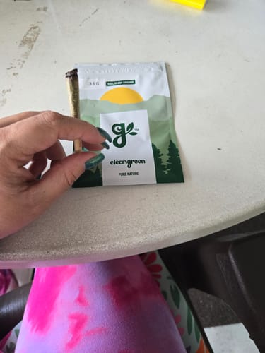 Customer holding a finished pre-roll next to the pouch of Roll Ready Ground flower.