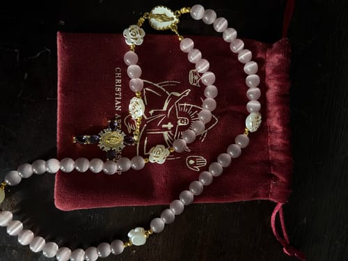 Reviewer's Cat's Eye & Rose Devotion Rosary with lustrous lavender beads displayed on a red velvet pouch.