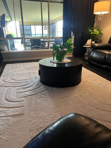 Customer's large Mellow Mat with a 3D carved pattern in their living room under a black coffee table.