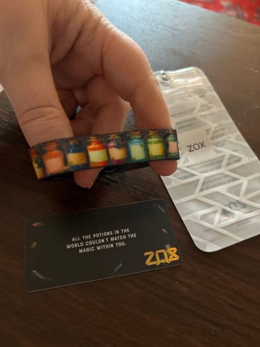 Reviewer holds the Made of Magic Bracelet, showing its colorful potion bottle design next to its themed card and pouch.