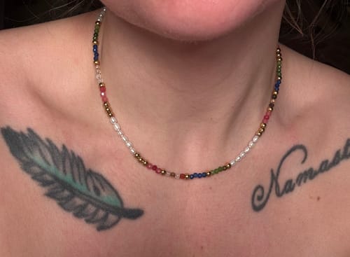 Customer wearing the colorful Kaya Necklace with pearl and gold beads around their neck.