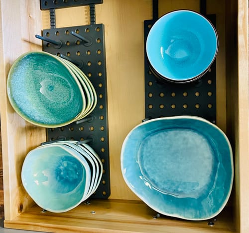 Reviewer's aqua blue stoneware plates and bowls with organic shapes stored in a kitchen drawer.