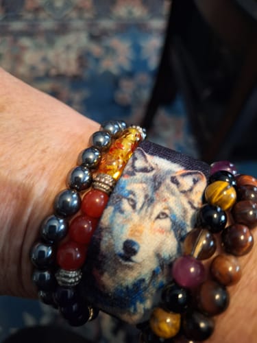 Close-up of a reviewer wearing the Still Here Bracelet, with a wolf tag and colorful beaded bands on their wrist.