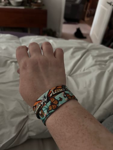 Close-up of a reviewer's wrist wearing the colorful Butterfly Kisses Bracelet with a butterfly pattern.