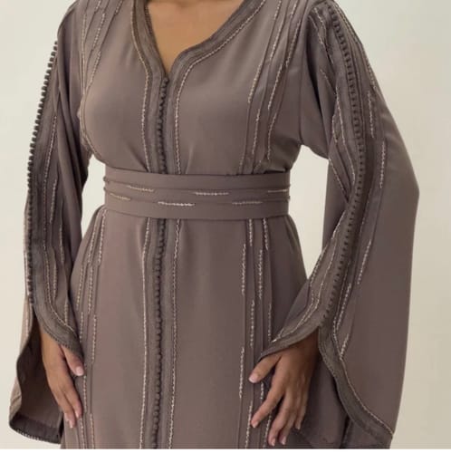 Customer wearing the elegant Caftan Malika Taupe, showing its detailed vertical embellishments and matching belt.