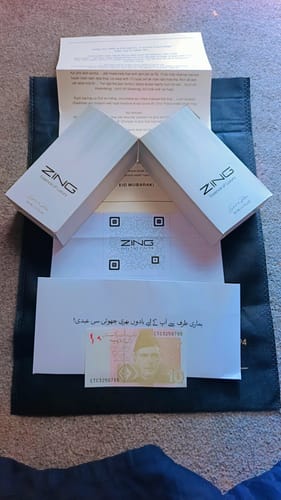 Customer's photo of the two white fragrance boxes from the Deal of the Month, laid out with paperwork and a small gift banknote.