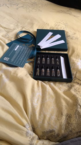 Customer's Discovery Set unboxed on a bed, showing the small fragrance vials and blotter strips.