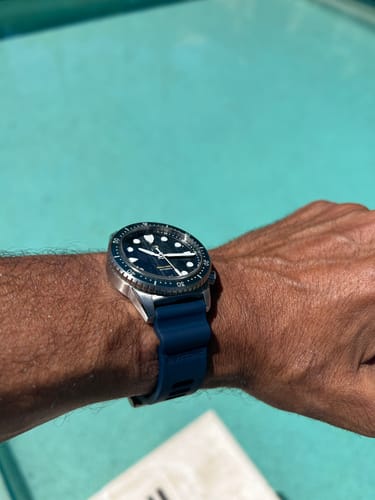 Customer's dive watch with the comfortable navy blue Divecore FKM rubber strap, worn on the wrist by a pool.