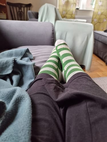 Recensent som vilar i en soffa med grön- och vitrandiga Diasocks stödstrumpor.