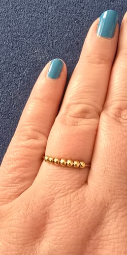 Rezensentin zeigt den vergoldeten Anti-Stress-Ring mit beweglichen Kugeln am Finger.