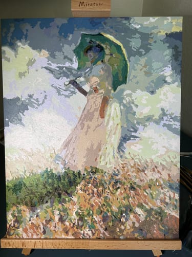 Customer's completed Woman with Umbrella paint-by-number canvas shown on an easel.