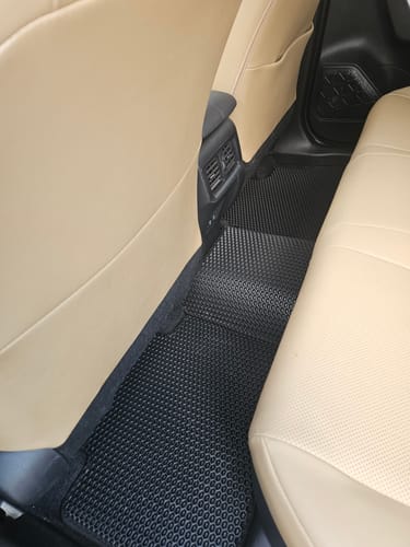 Recenzenta czarne, dopasowane dywaniki samochodowe na tylnej podłodze samochodu z beżowymi siedzeniami.