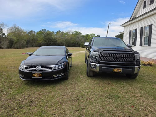 Reviewer's two black vehicles, a car and a truck, each displaying a custom Marines Metal License Plate on the front bumper.