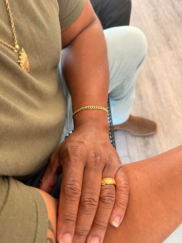A close-up of a customer's hand wearing the sandblasted gold Aureum ring on their finger.