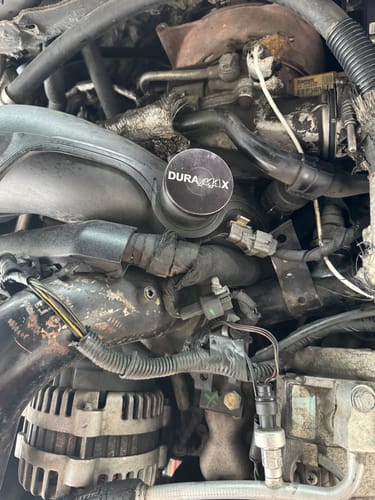 Customer's black Duramax Turbo Resonator Delete plug installed in an engine, with the etched logo visible.