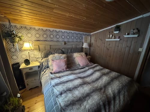 Anmelders Runa veggfliser som en dekorativ fondvegg bak sengen i et rustikt soverom på hytta.
