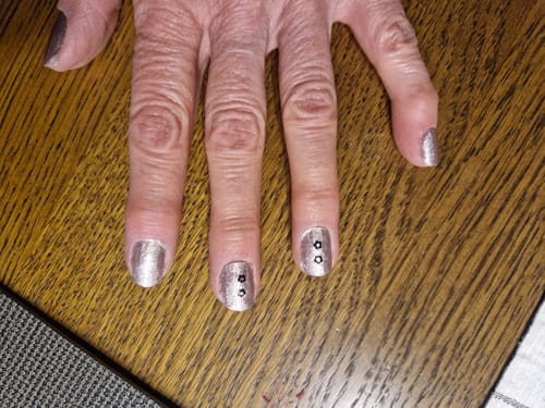 Hand einer Kundin, die die 'Neutral Love' UV-Gelfolien auf kurzen Nägeln trägt, mit herzförmigen Akzenten am Nagelbett.