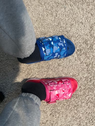 Customer wearing mismatched Mystery DracoSlides, one in a blue camo pattern and the other in a pink camo pattern.