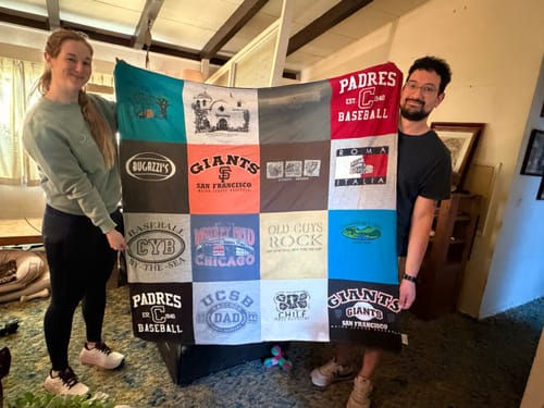 Two reviewers proudly holding their colorful Project Repat T-Shirt Quilt made from various logo t-shirts.