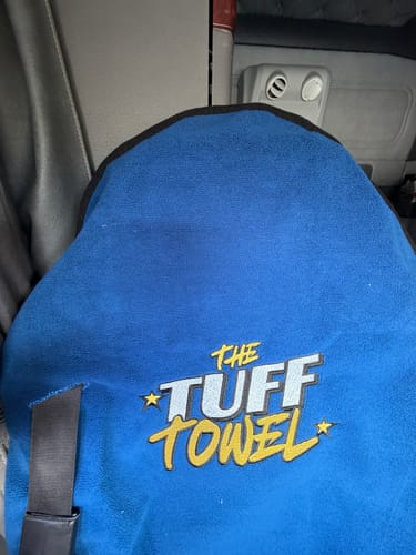 Reviewer's blue Tuff Towel seat cover on a car seat, modified with a cut for the seatbelt.