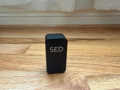 Customer's black Nano Case with 'SED' printed on it, standing upright on a wood floor.