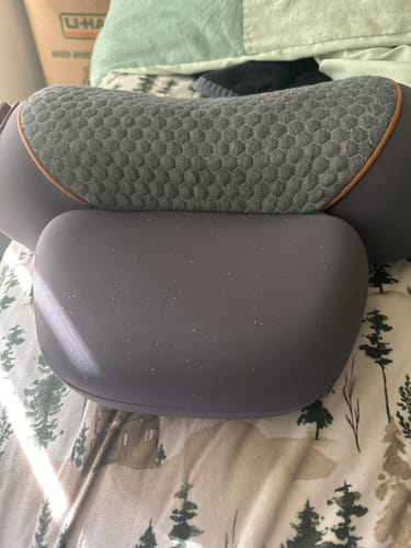 Customer's gray Original Callixe Thera Pillow with a textured surface, shown resting on a patterned bedspread.