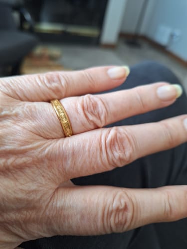A customer's hand showing the textured gold Aureum ring on their finger.