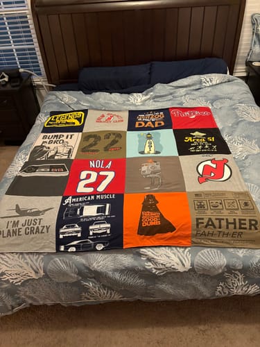 Customer's finished Project Repat T-Shirt Quilt, a colorful patchwork of shirts, spread across a bed.