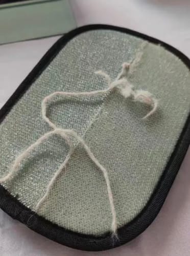 Close-up of a reviewer's Pet Hair Removal Glove, showing wear and pulled threads on the fabric surface.