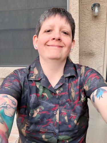 Reviewer smiling while wearing the dark, patterned 'The Valley of Teeth' short sleeve shirt.