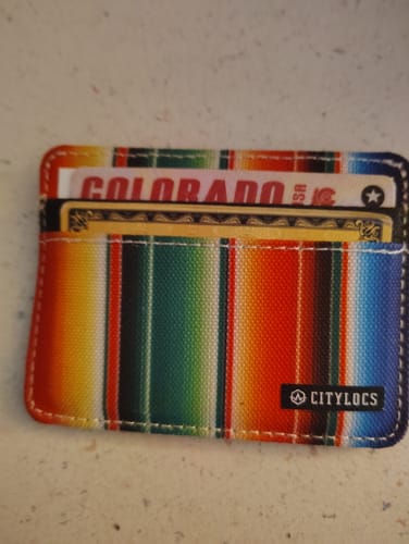 Customer's colorful Sarape Canvas Wallet with a striped pattern, shown holding several cards.