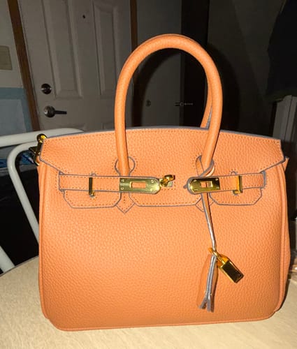 Customer's orange Warkin Bag sitting upright, showing its structured shape and pebbled leather.